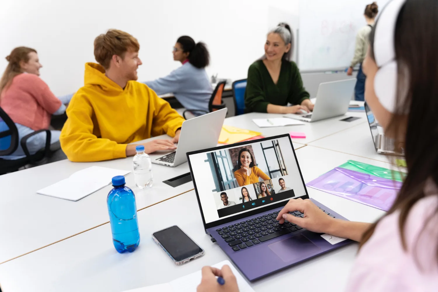 Students working with a laptop at a desk in a classroom
