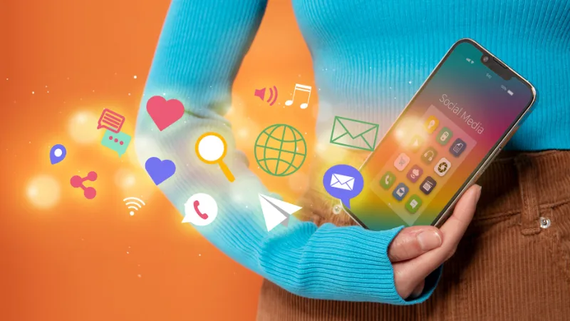 A smartphone with app icons and social media symbols flying out of it